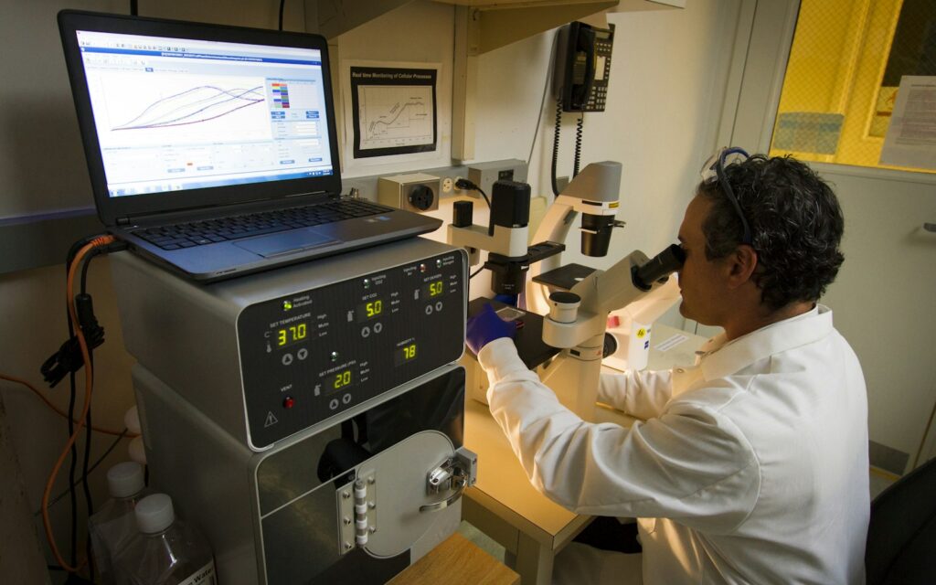 Cancer genomics researcher examining samples under a microscope in a laboratory