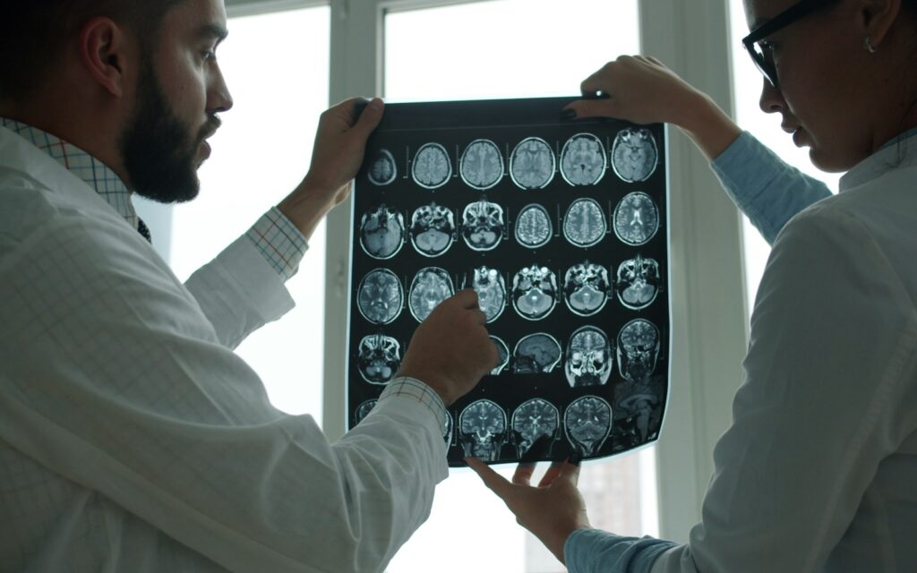 Two physicians reviewing brain MRI scans in a hospital
